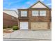 Stone-clad townhouse exterior featuring a two-car garage and meticulously maintained landscaping at 805 Pleasant Hill Nw Rd # 231, Lilburn, GA 30047