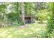 Backyard view featuring a storage shed surrounded by mature trees and lush greenery at 5400 Francis Ave, Stone Mountain, GA 30087