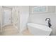 Spacious bathroom featuring white paneling, a glass enclosed shower, and a soaking tub at 1010 Fendley St, Woodstock, GA 30188