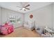 Bright bedroom featuring a ceiling fan, a crib, hardwood floors, and a large window at 1010 Fendley St, Woodstock, GA 30188