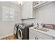 This laundry room has a front-load washer and dryer set, plus a sink and gray cabinets at 1010 Fendley St, Woodstock, GA 30188