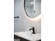 Close-up of bathroom sink with a modern black faucet and bright, illuminated round mirror at 3421 Fawn Trl, Marietta, GA 30066