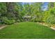 Expansive backyard featuring a lush lawn, mature trees, and a charming guest house at 240 Nacoochee Nw Dr, Atlanta, GA 30305
