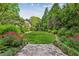 Lush backyard garden with manicured lawn and stone path leading to a house in the distance at 240 Nacoochee Nw Dr, Atlanta, GA 30305