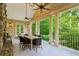 Covered patio featuring wood dining table and green metal chairs with a stone fireplace and beautiful wooded views at 240 Nacoochee Nw Dr, Atlanta, GA 30305