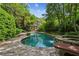Backyard pool with stone surround, landscaped greenery, and a charming house in the background at 240 Nacoochee Nw Dr, Atlanta, GA 30305