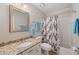 Well-lit bathroom with granite countertop, framed mirror, and bathtub with shower curtain at 310 Medridge Dr, Alpharetta, GA 30022
