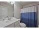Well-lit bathroom with a single sink, white cabinets, and shower-tub combination with a blue curtain at 3735 Hazel Ave, Cumming, GA 30040