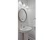 Stylish powder room featuring a pedestal sink, decorative mirror, and modern lighting fixture at 3735 Hazel Ave, Cumming, GA 30040