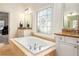 The primary bathroom has a large soaking tub with granite counters and plenty of natural light at 3820 Preserve Crossing Ln, Cumming, GA 30040
