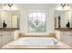 A soaking tub in a primary bathroom with granite counters and a beautiful window at 3820 Preserve Crossing Ln, Cumming, GA 30040