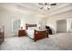 A large bedroom with tray ceilings, a comfy bed, a massage chair, and neutral tones at 3820 Preserve Crossing Ln, Cumming, GA 30040