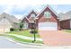 Attractive brick home featuring a manicured lawn, mature landscaping, and a brick driveway at 1570 Woodberry Run Dr, Snellville, GA 30078