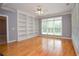 Bright living room featuring hardwood floors, built-in bookshelves, a ceiling fan, and a large window at 1570 Woodberry Run Dr, Snellville, GA 30078