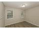A cozy bedroom with wood-look flooring, paneled walls, and natural light from two bright windows at 4631 Ben Hill Rd, Douglasville, GA 30134