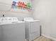 Bright laundry room featuring a white washer and dryer set, and a wire rack for organized storage at 361 Traditions Ln, Hampton, GA 30228