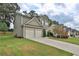 Well-manicured lawn of this two-story home and long concrete driveway leading to the attached garage at 5891 Buckner Creek Dr, Mableton, GA 30126