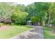 Driveway view of a charming home surrounded by mature trees and lush greenery, showcasing its peaceful setting at 2155 Cove Trl, Cumming, GA 30041