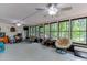 Spacious sunroom featuring views of the surrounding greenery through large windows, with multiple seating areas and ceiling fans at 2155 Cove Trl, Cumming, GA 30041