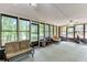 Bright sunroom with multiple windows offering serene views of the surrounding lush greenery and tranquil lake at 2155 Cove Trl, Cumming, GA 30041