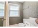 Clean, wallpapered bathroom with a toilet, window, and vanity at 837 Pine Ridge Dr, Lawrenceville, GA 30043