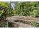 An outdoor deck surrounded by trees, featuring a built-in fire pit and stone accents at 837 Pine Ridge Dr, Lawrenceville, GA 30043