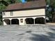 Exterior shot showcasing a three-car garage with individual bays on a property with mature trees at 1455 Stone Mill Trce, Stone Mountain, GA 30083