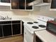 Image showing a kitchen with black cabinets, white countertops, and a white stove at 1455 Stone Mill Trce, Stone Mountain, GA 30083