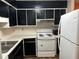 Shows a kitchen with black cabinetry, white appliances, and white countertops at 1455 Stone Mill Trce, Stone Mountain, GA 30083