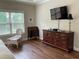 Comfortable bedroom with wood floors, TV, dresser, and chair with view at 1790 Nestledown Dr, Cumming, GA 30040