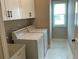 Practical laundry room with white washer and dryer and ample cabinet space at 1790 Nestledown Dr, Cumming, GA 30040