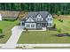 Aerial view of home with landscaped yard, long driveway, patio with fire pit and wooded area at 411 Oakleigh Ave, Woodstock, GA 30188