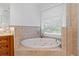 Bright bathroom features a soaking tub with tile surround, and natural light at 7535 Antique Barn Ave, Cumming, GA 30041