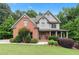 Charming two-story home with a brick and gray shingle exterior, complemented by a lush, well-manicured front yard at 7535 Antique Barn Ave, Cumming, GA 30041