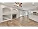 Open-concept living room featuring wood floors, a fireplace, built-in shelving, and access to a kitchen at 6625 Eagle Pt, Suwanee, GA 30024