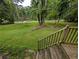 View of the expansive front yard featuring a mix of lush greenery, mature trees, and a gently sloping landscape at 512 S Holly Springs Rd, Woodstock, GA 30188