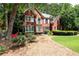 Traditional brick house with well-maintained lawn, lush trees, and pretty flower beds at 1558 Amberwood Creek Nw Dr, Kennesaw, GA 30152