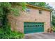 Side view of brick home with green garage door complemented by lush landscaping at 3206 Pyrite Sw Cir, Atlanta, GA 30331