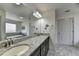 Stylish bathroom featuring double sinks with granite countertop, dark wood cabinetry, and large mirror at 4590 Sierra Creek Dr, Hoschton, GA 30548