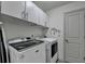 Well-organized laundry room with overhead cabinets, modern washer and dryer, and decorative wall art at 4590 Sierra Creek Dr, Hoschton, GA 30548