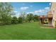 Serene backyard with a spacious lawn, partial wooden deck, and mature trees, creating a private retreat at 506 Spring View Dr, Woodstock, GA 30188