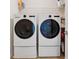 Modern laundry room with front loading washer and dryer set, shelf storage, and tiled floor at 506 Spring View Dr, Woodstock, GA 30188