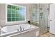 Modern bathroom featuring a soaking tub, walk-in shower, and natural light from a large window at 1223 Gathering Oaks Se Ct, Mableton, GA 30126