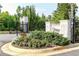 Elegant community entrance featuring lush landscaping, beautiful flower beds, and stone signage at 330 Carriage Glen Ln, Woodstock, GA 30188