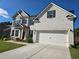 Two-story white brick home featuring an attached two-car garage and well-maintained landscaping at 3332 Grace Farm Ln, Buford, GA 30519