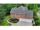 View of the brick home featuring an attached two-car garage with a driveway and landscaped backyard at 12130 Helleri Holw, Alpharetta, GA 30005