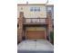 Townhome featuring an attached two-car garage with a brick facade and balcony above at 1668 Sabastian Ne Pt, Atlanta, GA 30329