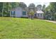 Two-story home with tan siding, teal shutters, a metal roof, and a well-manicured lawn with mature trees at 165 Country Mill Ln, Stockbridge, GA 30281
