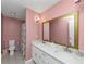 Pink bathroom featuring double sinks, marble countertops, and decorative shower curtain at 6744 Rockbridge Rd, Stone Mountain, GA 30087