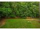 Large grassy backyard, enclosed by a wood fence and surrounded by mature trees at 2732 Dahlonega Trl, Austell, GA 30106